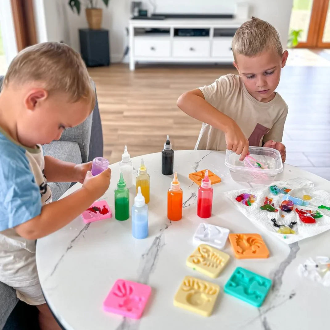 Adult hands squeezing colored gel into a mold above a bowl of water